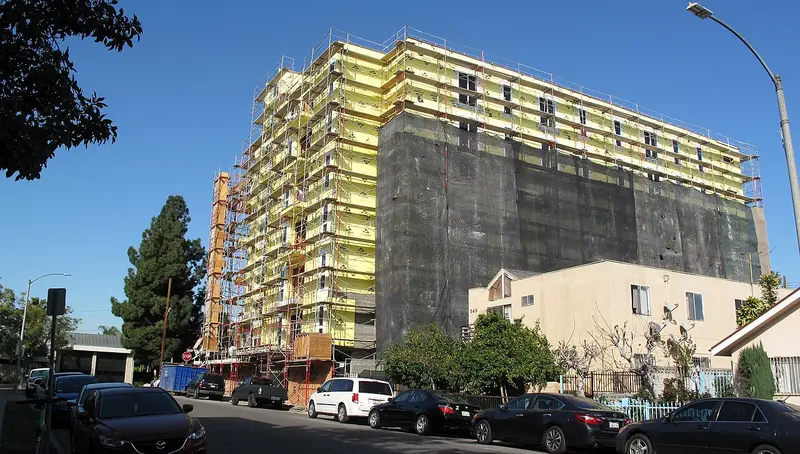 A mid-rise apartment building wrapped in scaffolding on Melrose Avenue