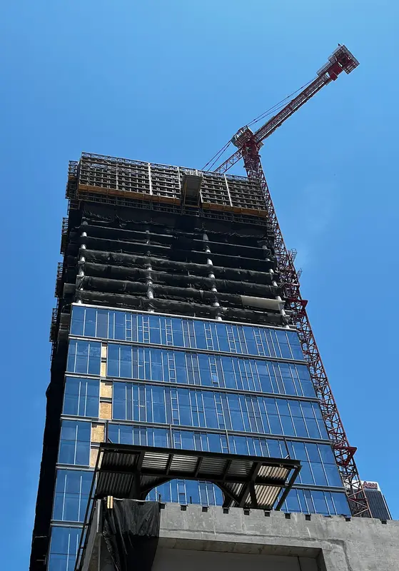 A glass tower rising with a tower crane at its top in downtown Los Angeles