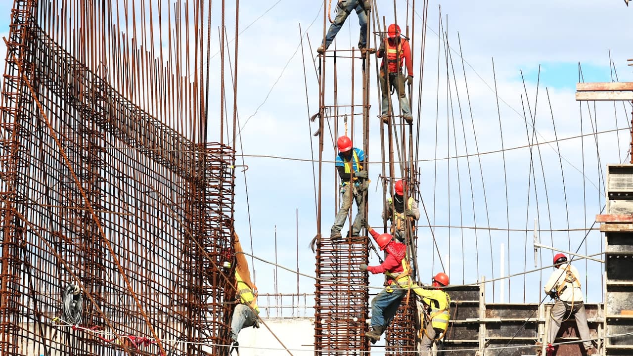 Workers in hard hats tying rebar on a concrete structure