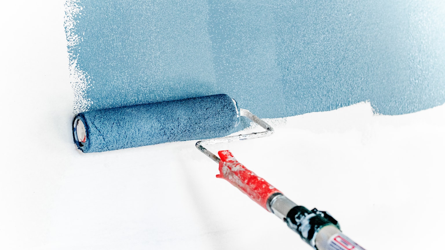 A paint roller applying a fresh coat to an interior wall
