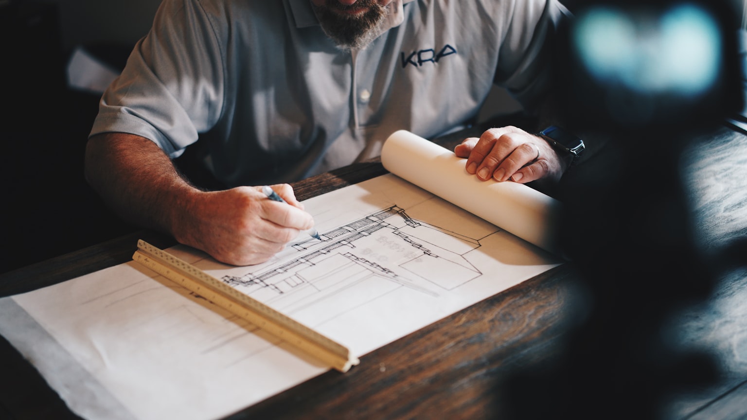 A person marking up construction drawings at a desk
