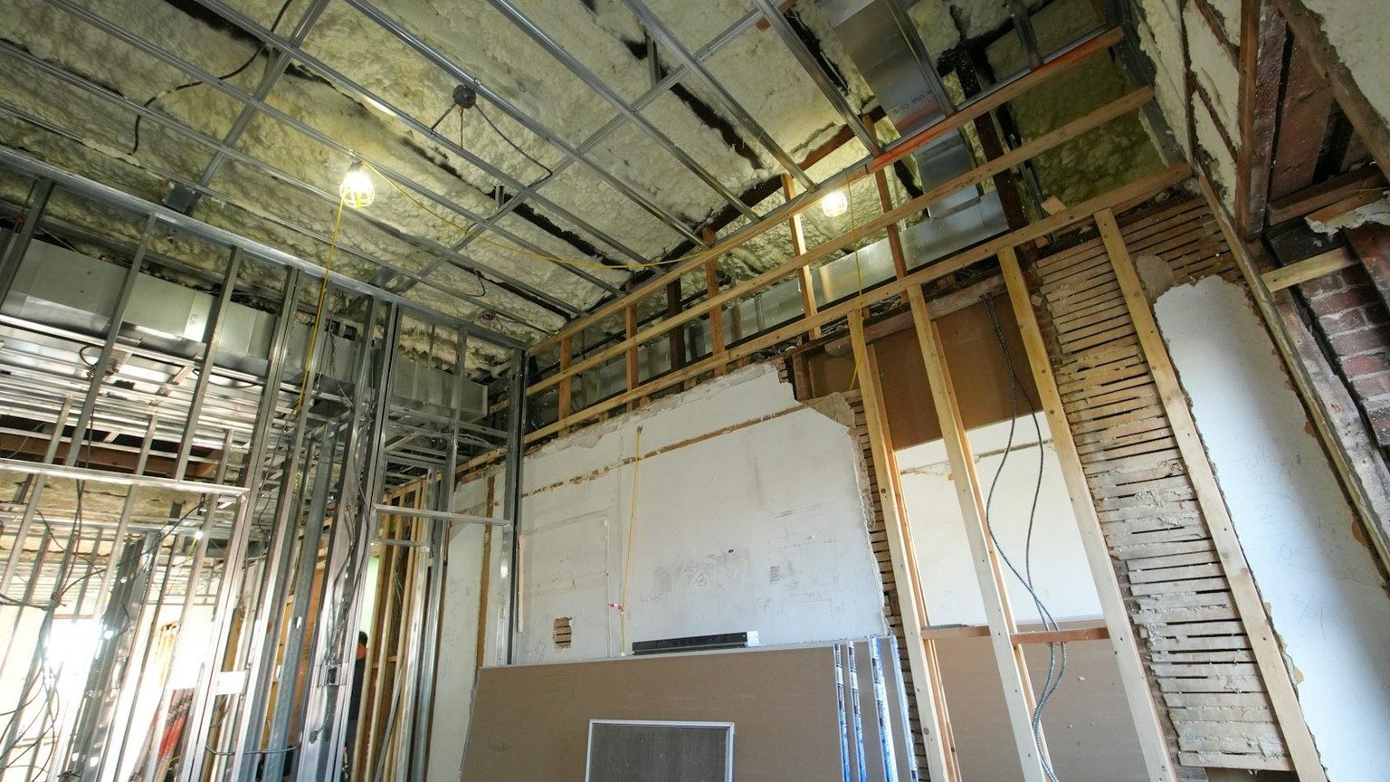 Gutted interior mid-renovation, with exposed studs, spray foam insulation and ceiling framing